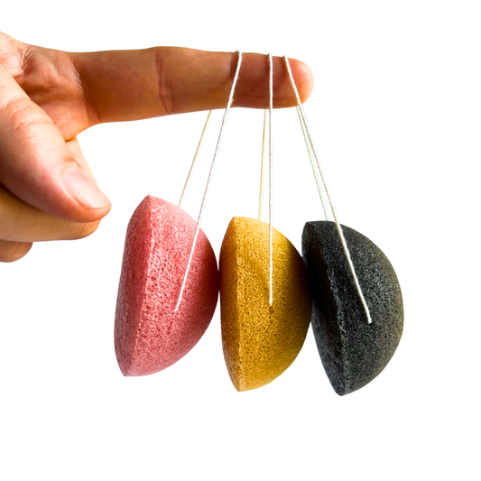 Three colorful konjac sponges hanging by strings against a white background